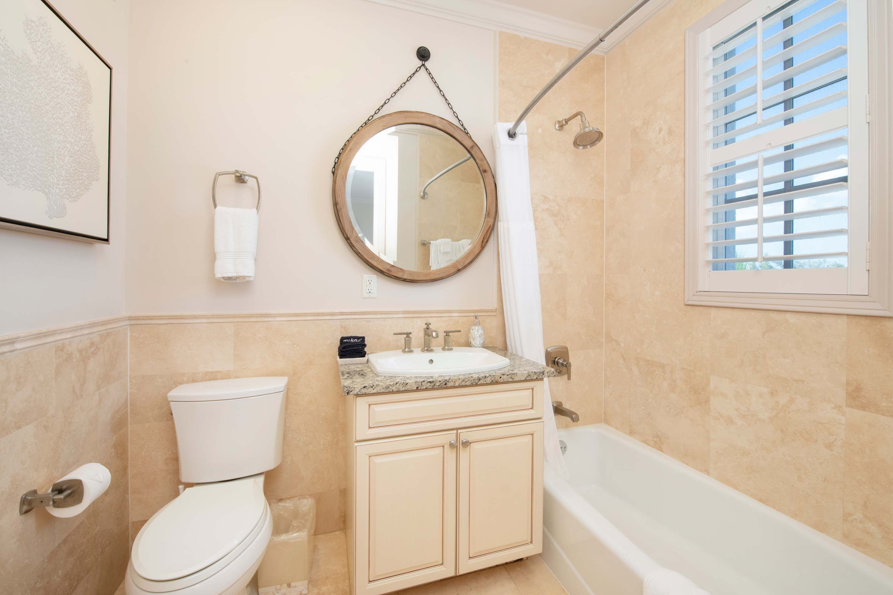 A bathroom with a toilet, sink, vanity, and bathtub.