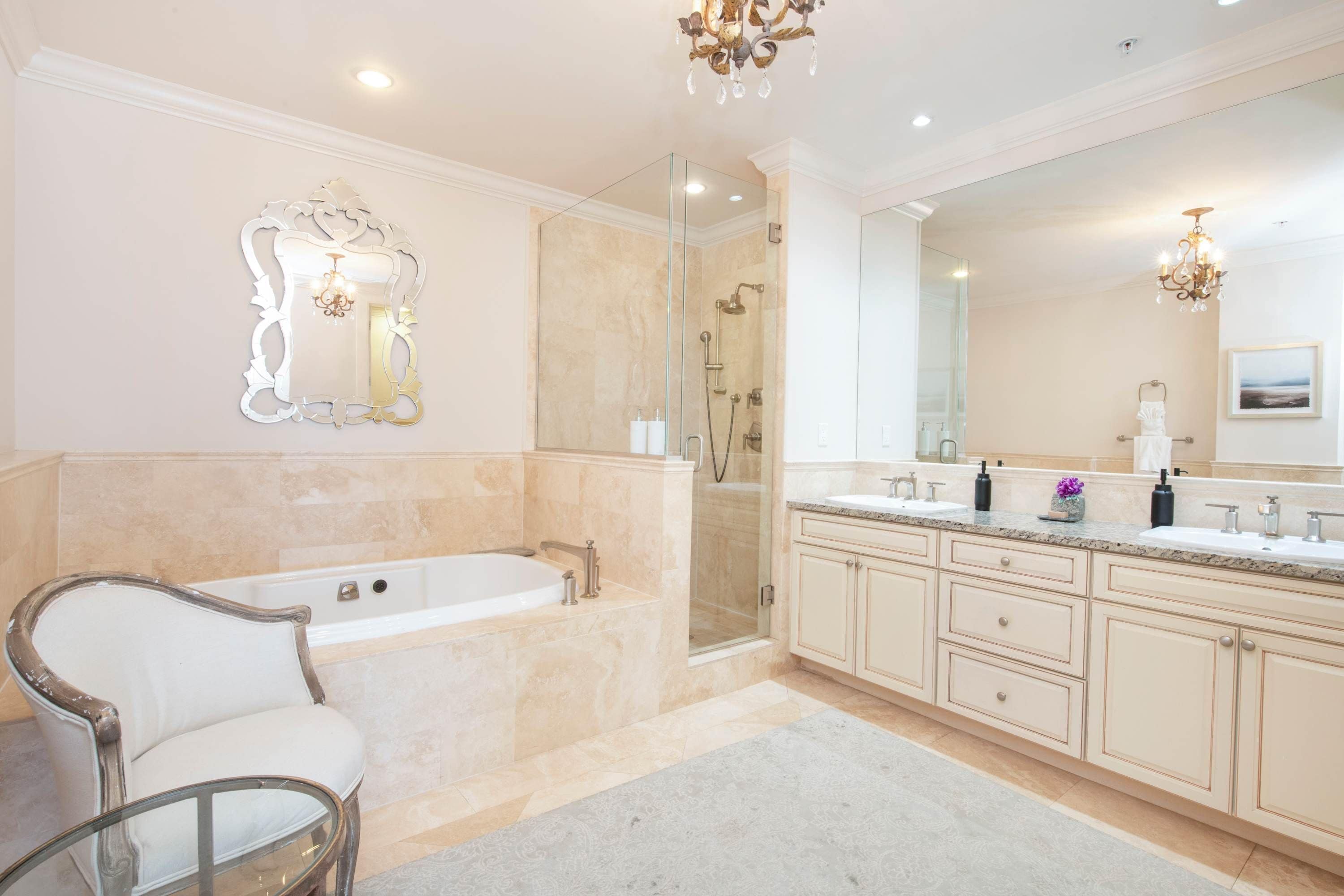 Een luxe badkamer met een vrijstaand bad, een douche met glazen wanden en een ruime wastafel met meerdere wasbakken.