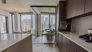 Una cocina moderna con una isla grande, armarios de madera oscura y vistas de la ciudad a través de amplios ventanales.