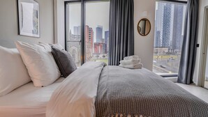 Una habitación de hotel con una cama grande, vistas a la ciudad y un cuadro enmarcado en la pared.