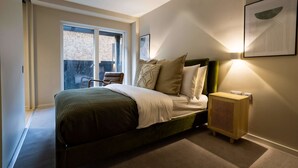 Una camera da letto con un letto, un comodino, una lampada a parete e una finestra.