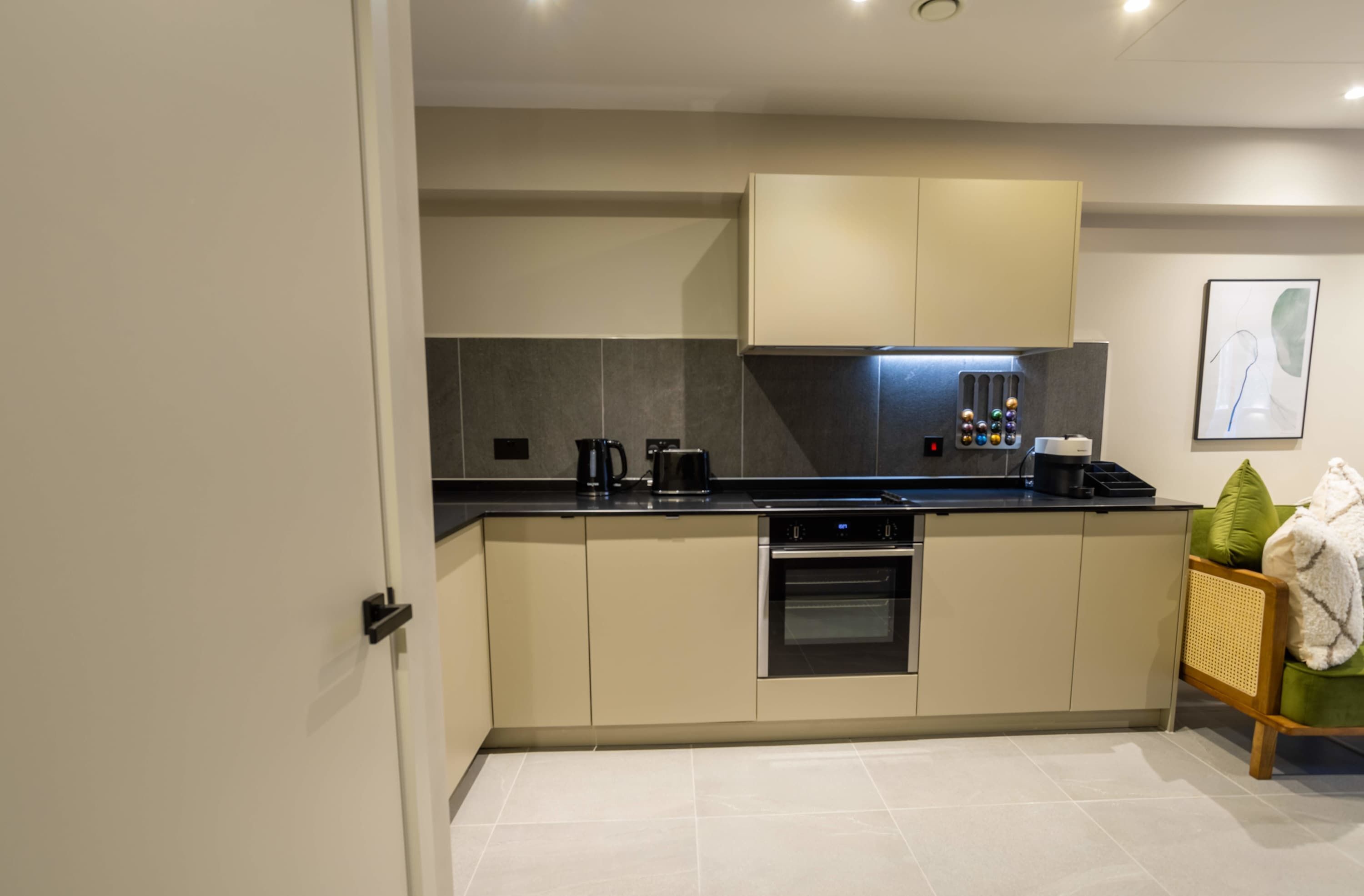A modern kitchen with a built-in oven, a coffee maker, and a kettle.