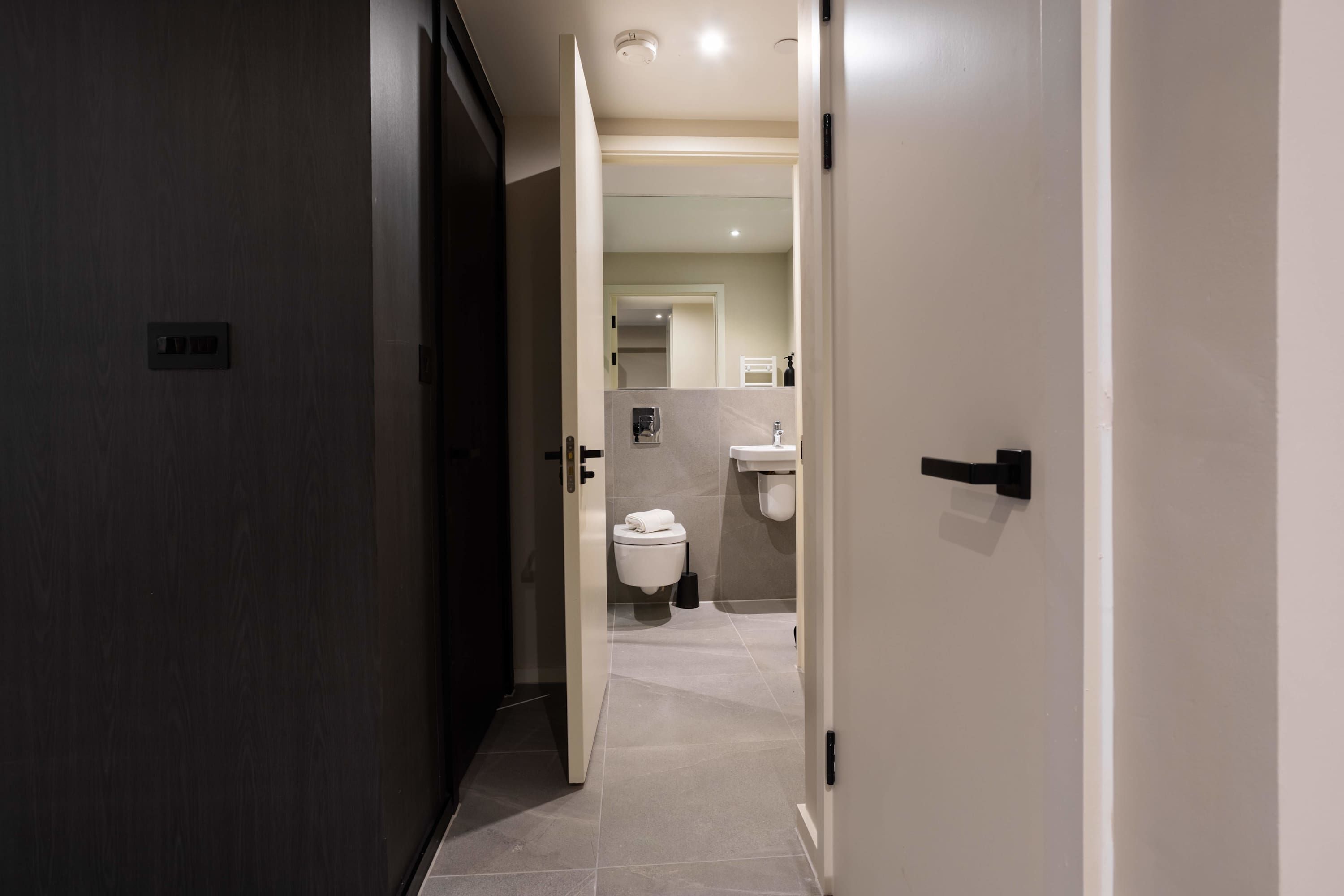 A modern bathroom with a toilet, sink, and mirror.