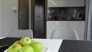 A dining table with a plate of green apples, a remote control, and a gray placemat. - House on Water in Dziwnow Near Clean Beach (Dziwnów)