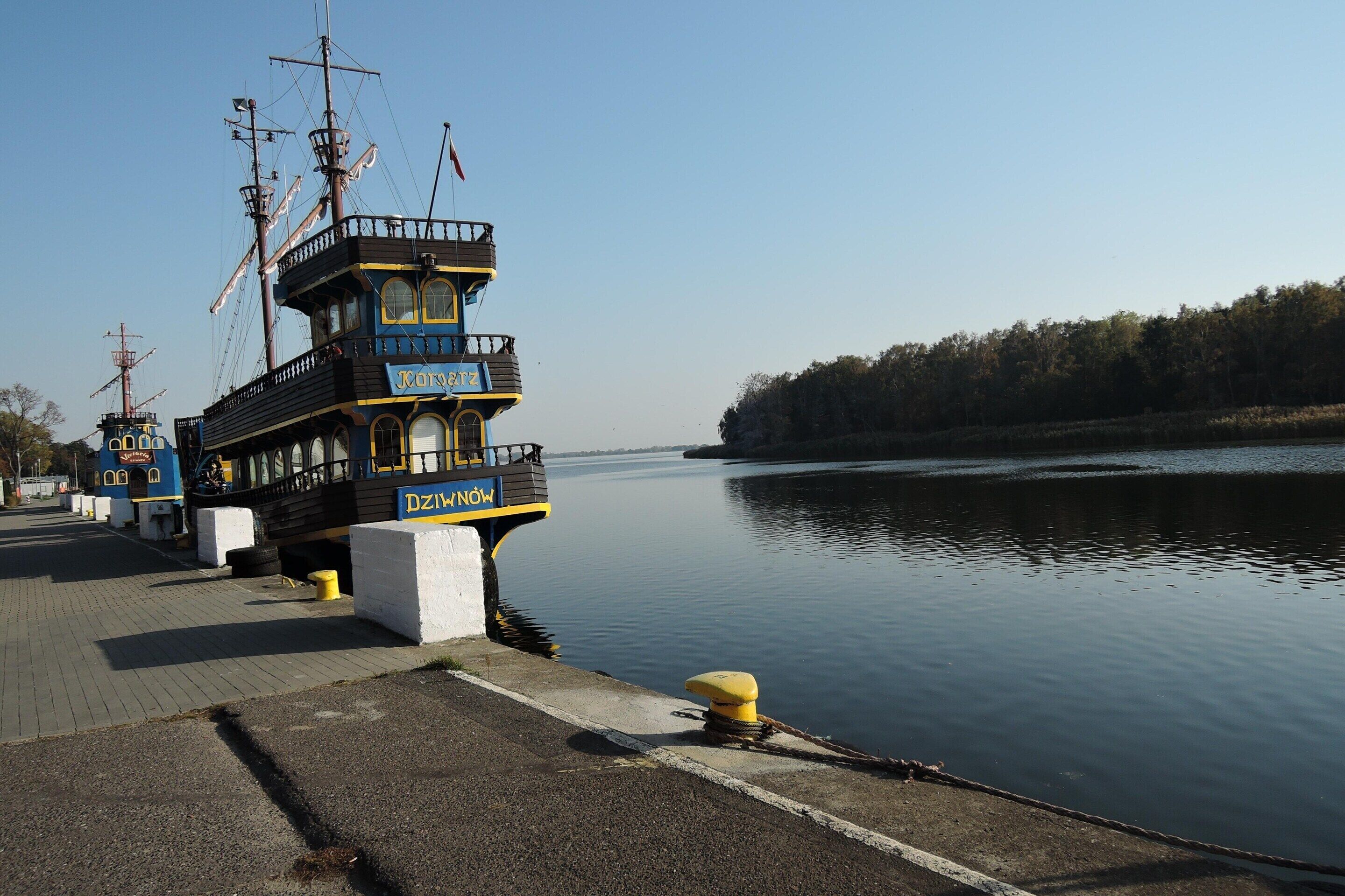 A docked ship with a cabin structure, a name plaque, and a flag.