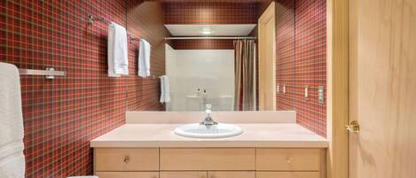 A bathroom with a red and black checkered wall, a white sink, and wooden cabinets.