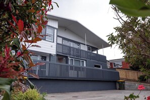 Un moderno edificio residencial de dos pisos con techo plano, balcones y entrada protegida por un portón.