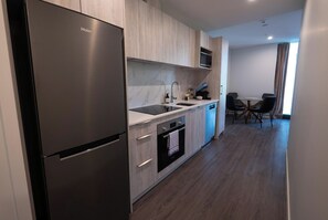 A modern kitchen with a Haier refrigerator, a microwave, a sink, and a dishwasher. There is a dining area with a table and chairs. - Class and comfort right the the heart of Parnell. (Auckland)