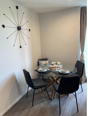 Un coin repas comprenant une table en verre, quatre chaises et une horloge murale au design moderne.