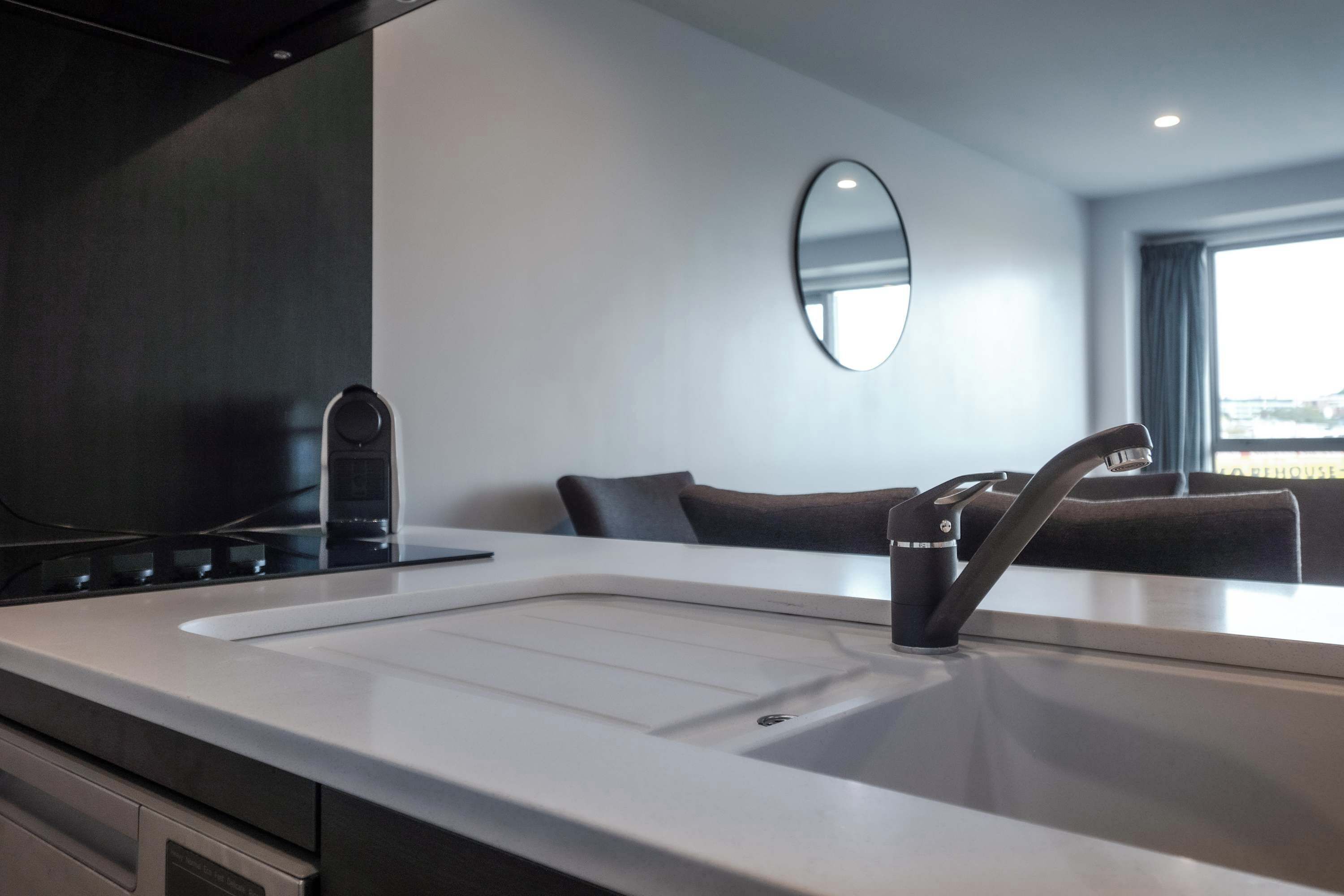 A modern kitchen with a white countertop, a black faucet, and a built-in oven.
