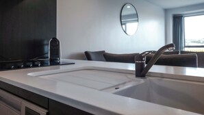 A modern kitchen with a white countertop, a black faucet, and a built-in oven.