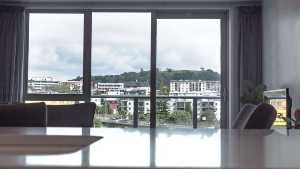 A room with a large window, a dining table, and a potted plant.