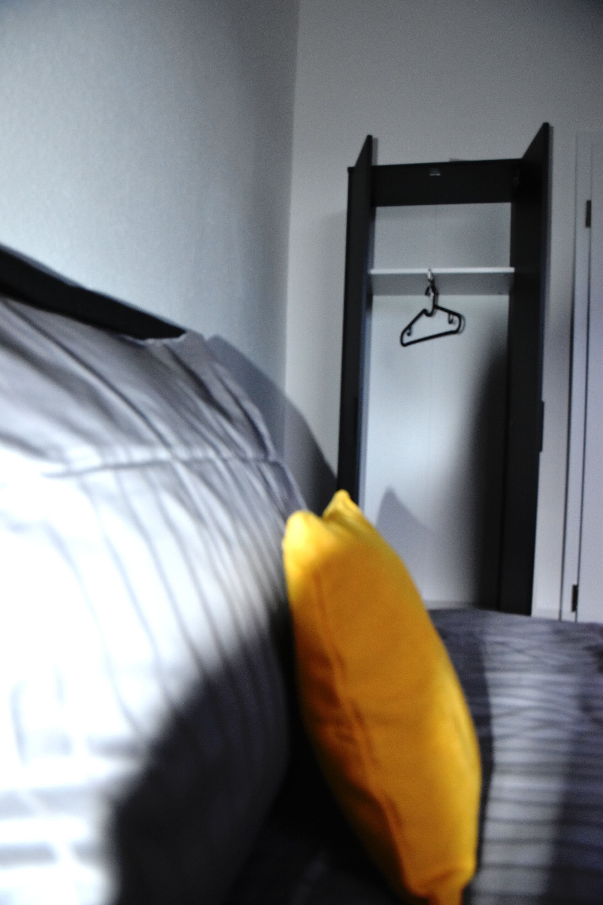 Een bed met een zwart-wit gestreepte dekbedovertrek en één geel kussen.