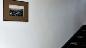 Una escalera con barandilla y un muro con dos cuadros enmarcados.