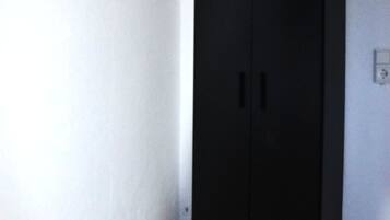 Una habitación con un armario negro, suelo de mármol y pared blanca.