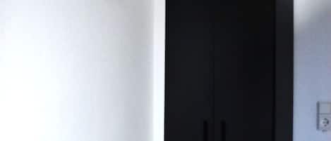 Una habitación con un armario negro, suelo de mármol y pared blanca.