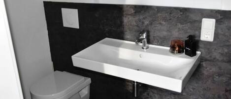 A bathroom with a white sink, black countertop, and a white toilet.