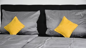 Una cama con ropa de cama gris y dos almohadas amarillas.