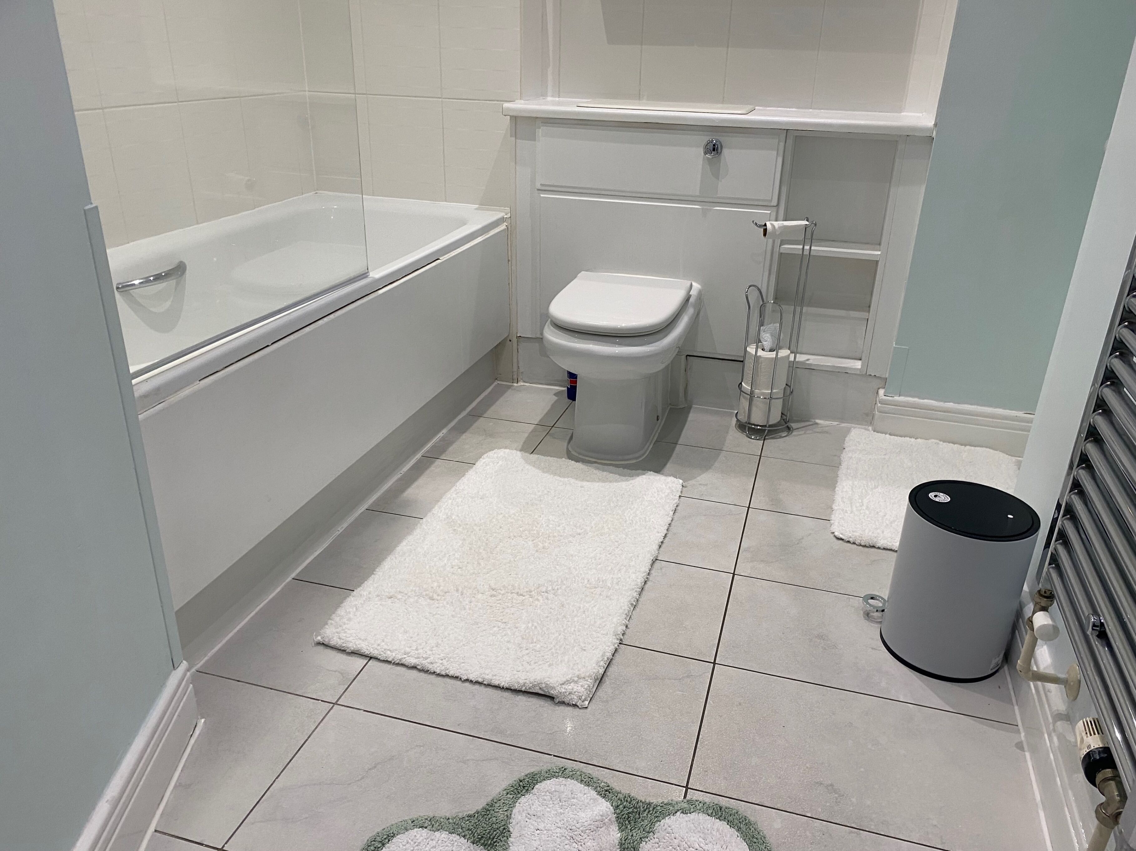 Un baño moderno con bañera, inodoro y un cubo de basura.