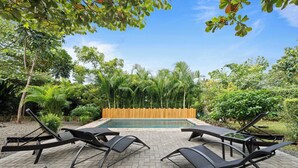 A poolside area with lounge chairs, a wooden fence, and lush greenery. - Private 4BR Oasis + Pool – Near Playa Grande Beach (Playa Grande)
