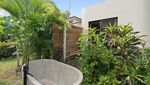 A concrete bathtub in a garden with lush greenery and a modern building in the background. - Private 4BR Oasis + Pool – Near Playa Grande Beach (Playa Grande)