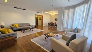 A modern living room with a sofa, armchairs, a coffee table, and a dining area with chairs and a table. - Maison 7 New Cairo  (New Cairo)