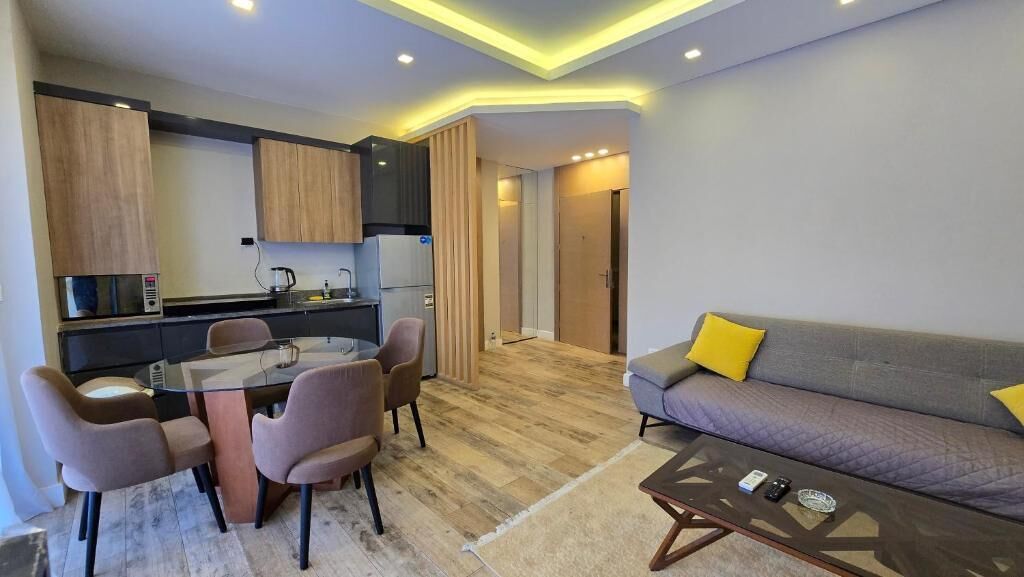 Eine moderne Wohnung mit Essbereich, Küchenzeile, Sofa und einem Glastisch.