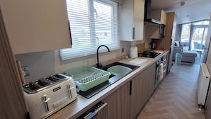 A compact kitchen with a toaster, sink, and a window with blinds.