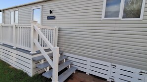 A mobile home with a white exterior, a front porch with steps, and a mailbox.
