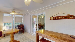 A dining area with a wooden table and chairs, a ceiling fan, and a sign reading "Captains Table".