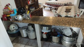 A kitchen with granite countertops, stainless steel pots, and a dining area with a table and chairs. - House in the Central Beach of Guaratuba (Guaratuba)