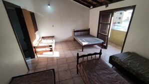 A dormitory room with two single beds, a small table, and a window. - House in the Central Beach of Guaratuba (Guaratuba)