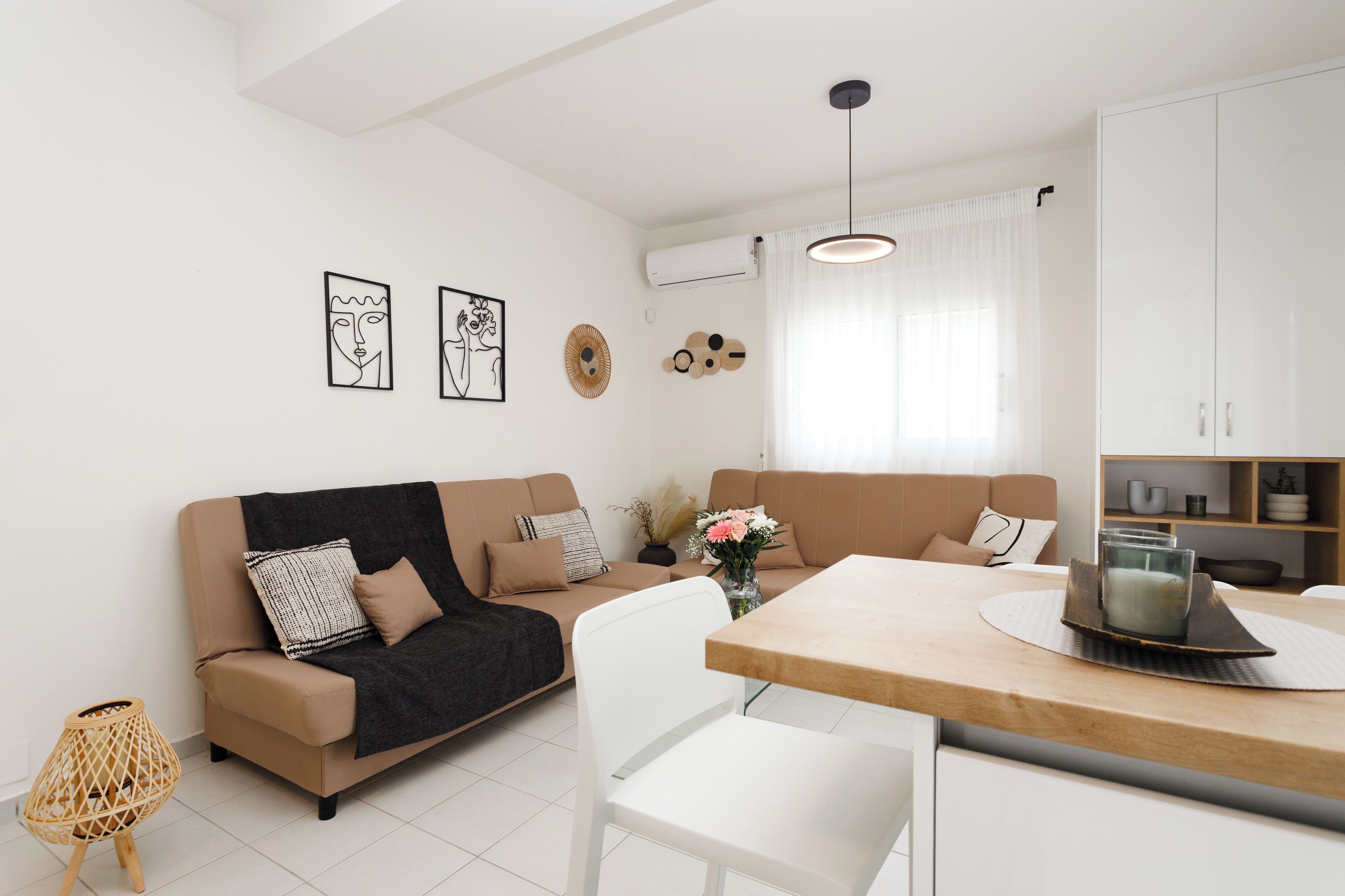 A modern living room with a sofa, a dining table, and a kitchen area.