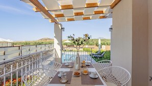 A terrace with a table set for two, overlooking a pool and a mountainous landscape. - Panor Villas (Rethymno)