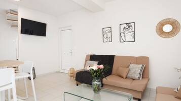 Una sala de estar moderna con una mesa de centro de vidrio, un sofá color beige y un televisor montado en la pared.