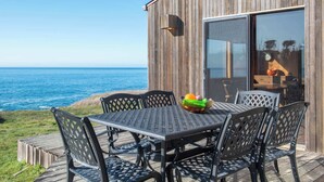 A wooden deck with a table and chairs overlooking the ocean. - Sea Ranch Oceanfront 3BR | Hot Tub | Sleeps 6 (Sea Ranch)