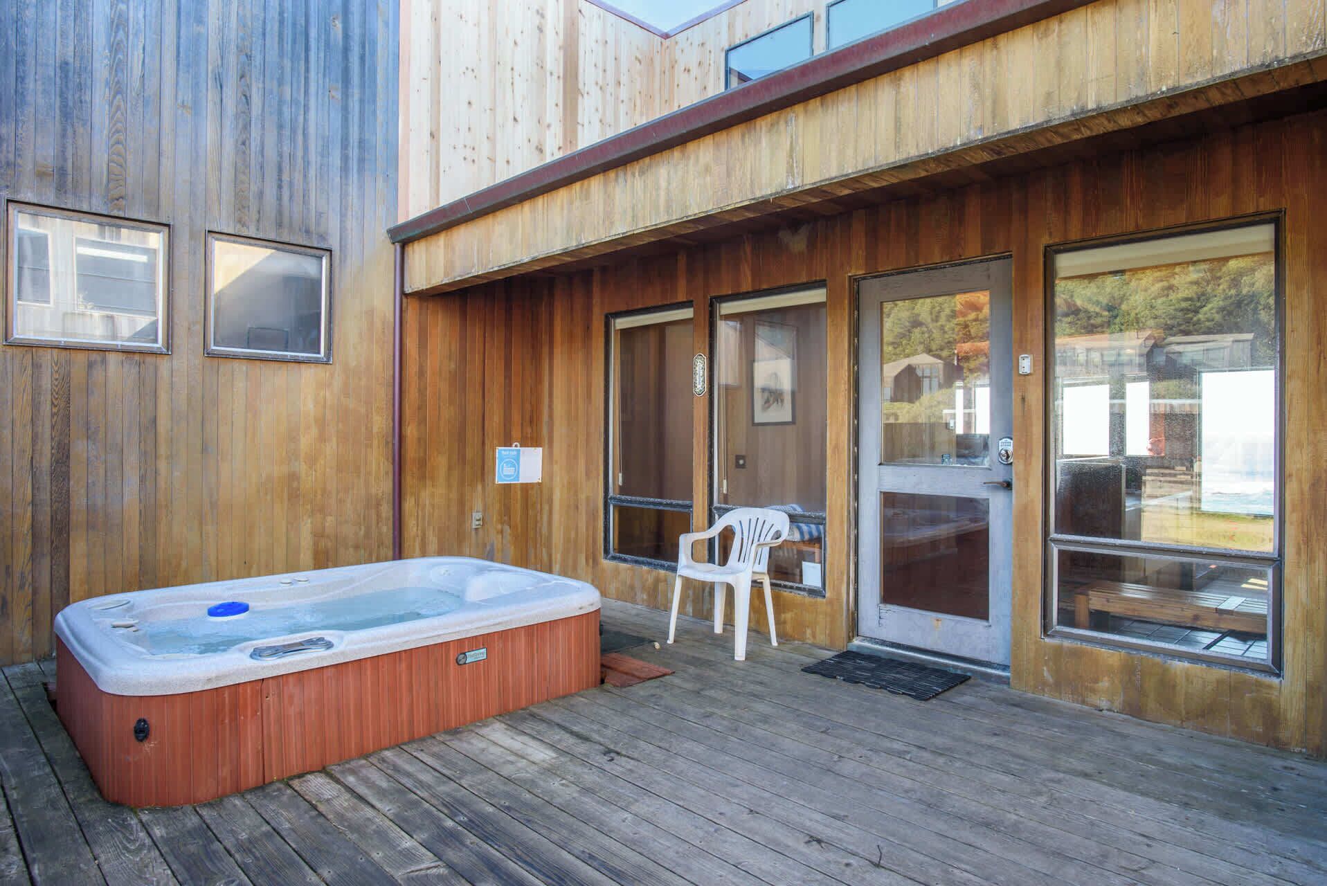 Eine Holzterrasse mit Whirlpool und weißem Stuhl.