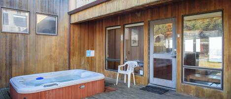 Eine Holzterrasse mit Whirlpool und weißem Stuhl.