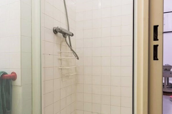 A shower with a glass door, white tiled walls, and a towel rack. - Studio cabin Grenoble city center (Grenoble)