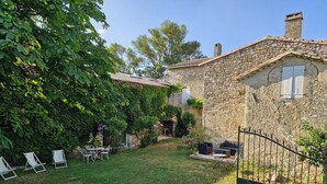 A stone house with a garden, outdoor seating, and a metal gate.