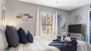 A bedroom with a bed, pillows, a TV, and a window with curtains. - Fisherman's Lure (Branson)