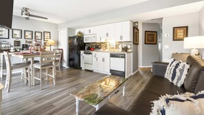 A modern kitchen with white cabinets, a black refrigerator, and a dining area with a wooden table and chairs. - Fisherman's Lure (Branson)