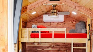 Une chambre mansardée chaleureuse, avec un lit superposé, un bureau et une chaise.