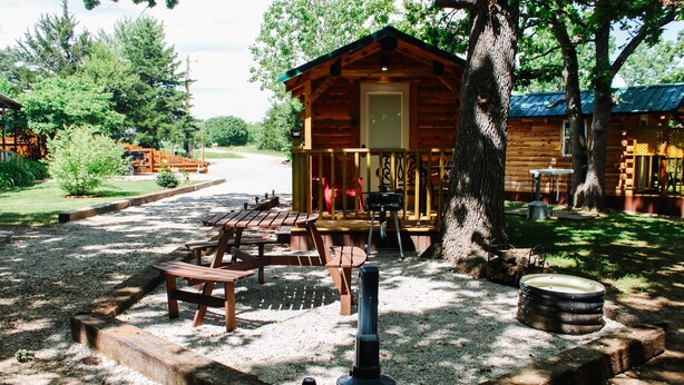 Une cabane rustique dotée d’une véranda, de tables de pique-nique et d’un poêle à bois.