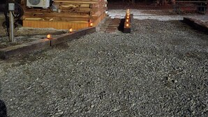 Une cabane en bois avec une allée en gravier et un foyer extérieur.