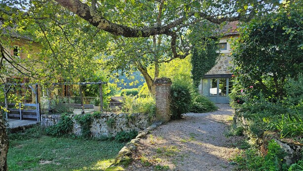 A rustic stone pathway leading to a stone building with a tiled roof, surrounded by lush greenery and a wooden pergola. - Domaine de Clarat, Béalière gîte in the heart of green Ardèche (Lafarre)