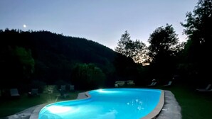 A swimming pool with a stone edge, surrounded by a grassy area and trees. - Domaine de Clarat, Béalière gîte in the heart of green Ardèche (Lafarre)