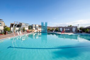 A swimming pool with a diving platform, lounge chairs, and a building with a 'CLUB' sign.