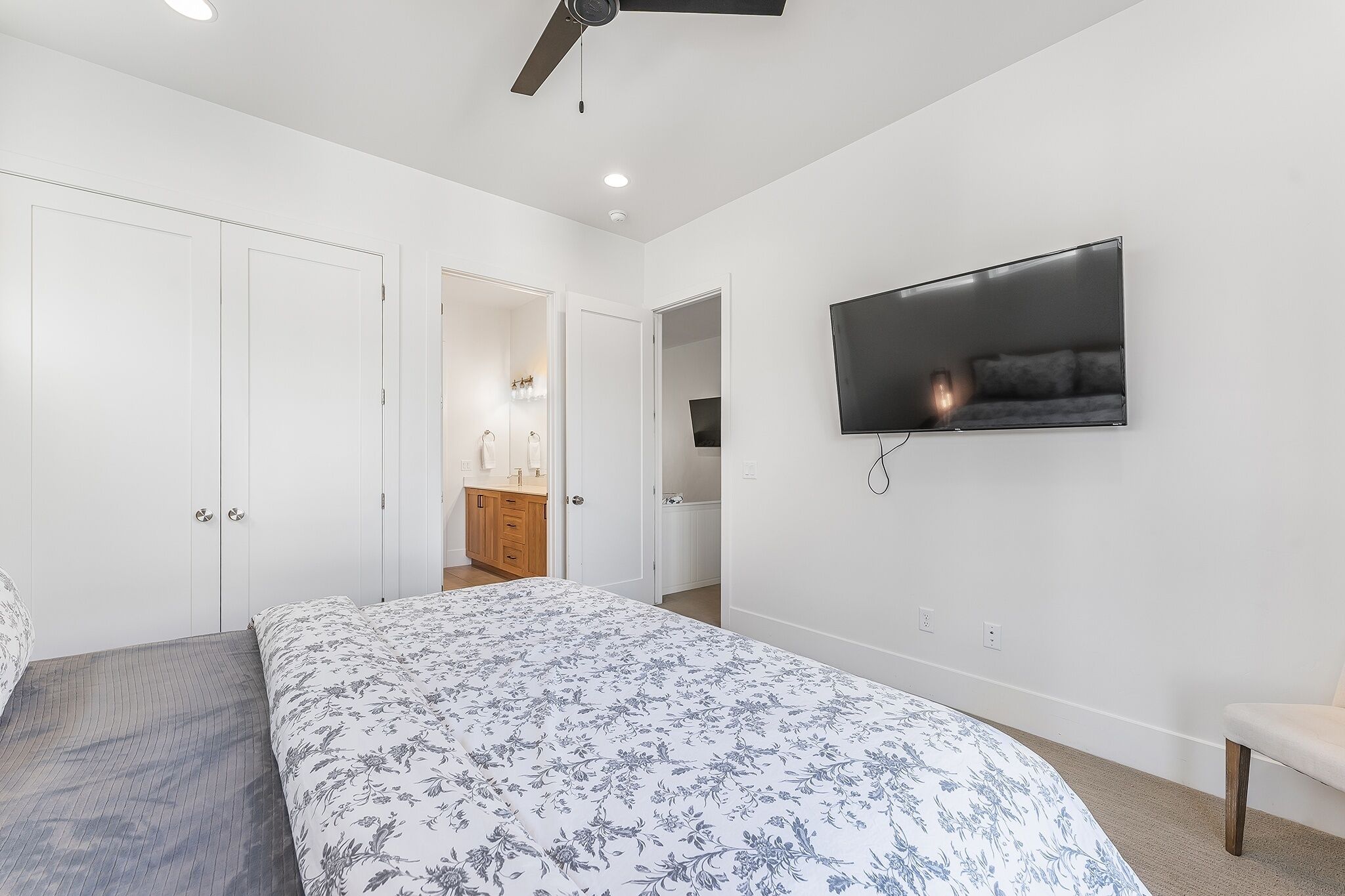 Una camera da letto con un letto, una TV a parete e una ventola a soffitto.