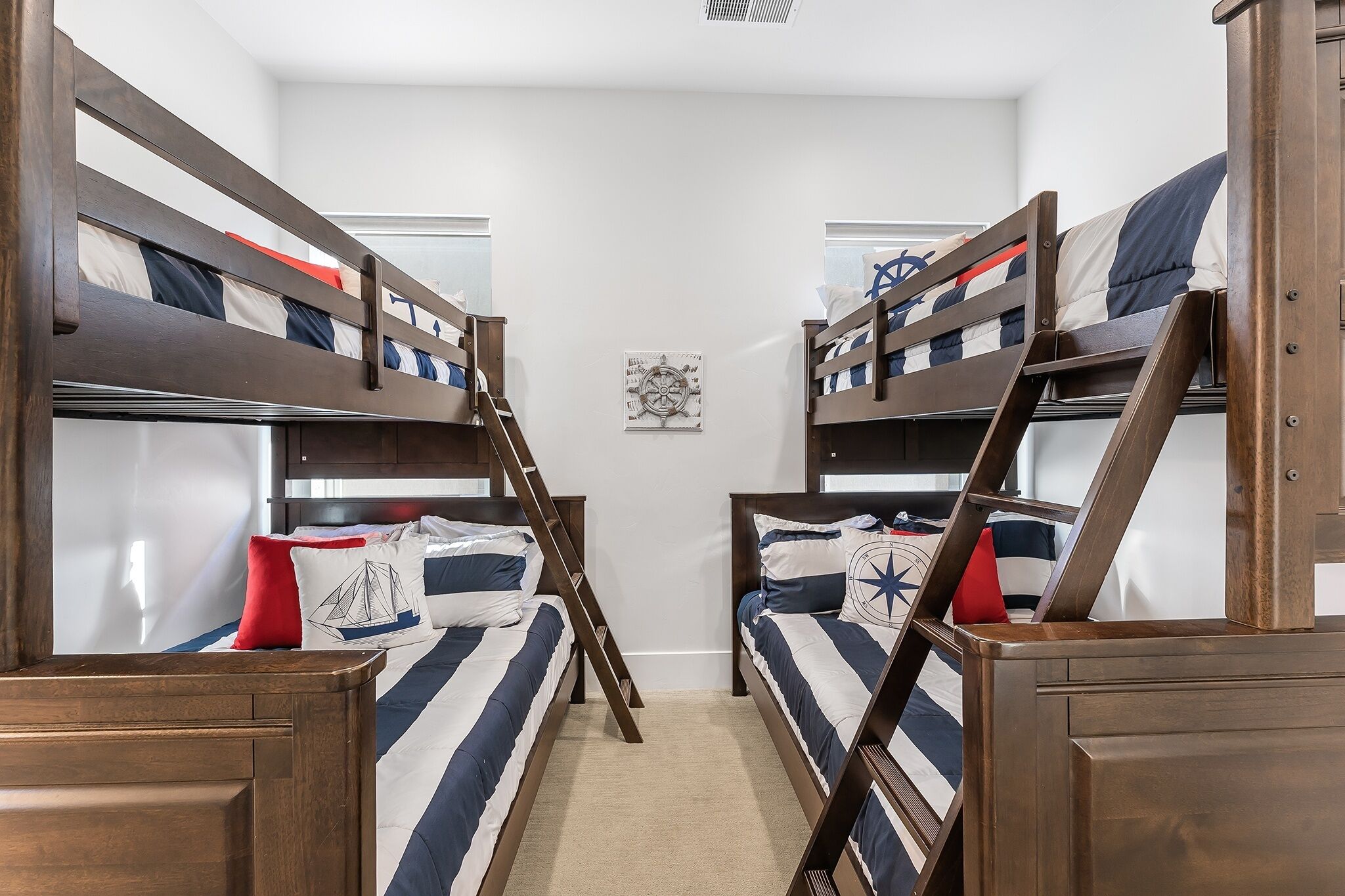 Un dormitorio con literas, dos literas, una escalera y una decoración de temática náutica.